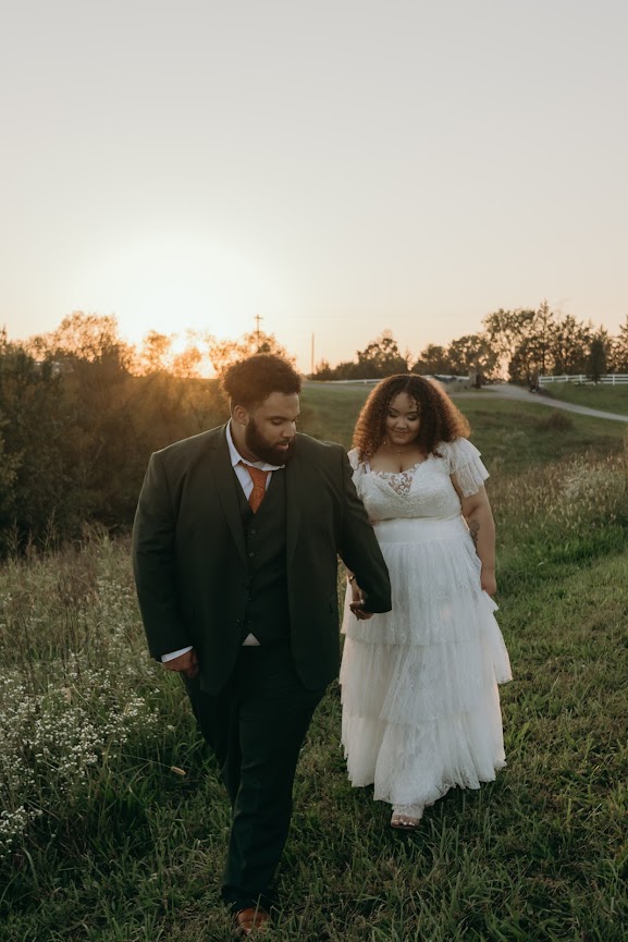 A newlywed couple walking hand in hand through a meadow at sunset, embracing the intimacy of a micro-wedding at Willow and Stone Events